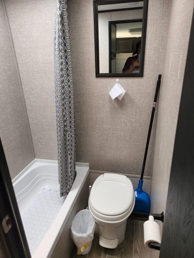 A toilet and tub in a bathroom with a mirror.