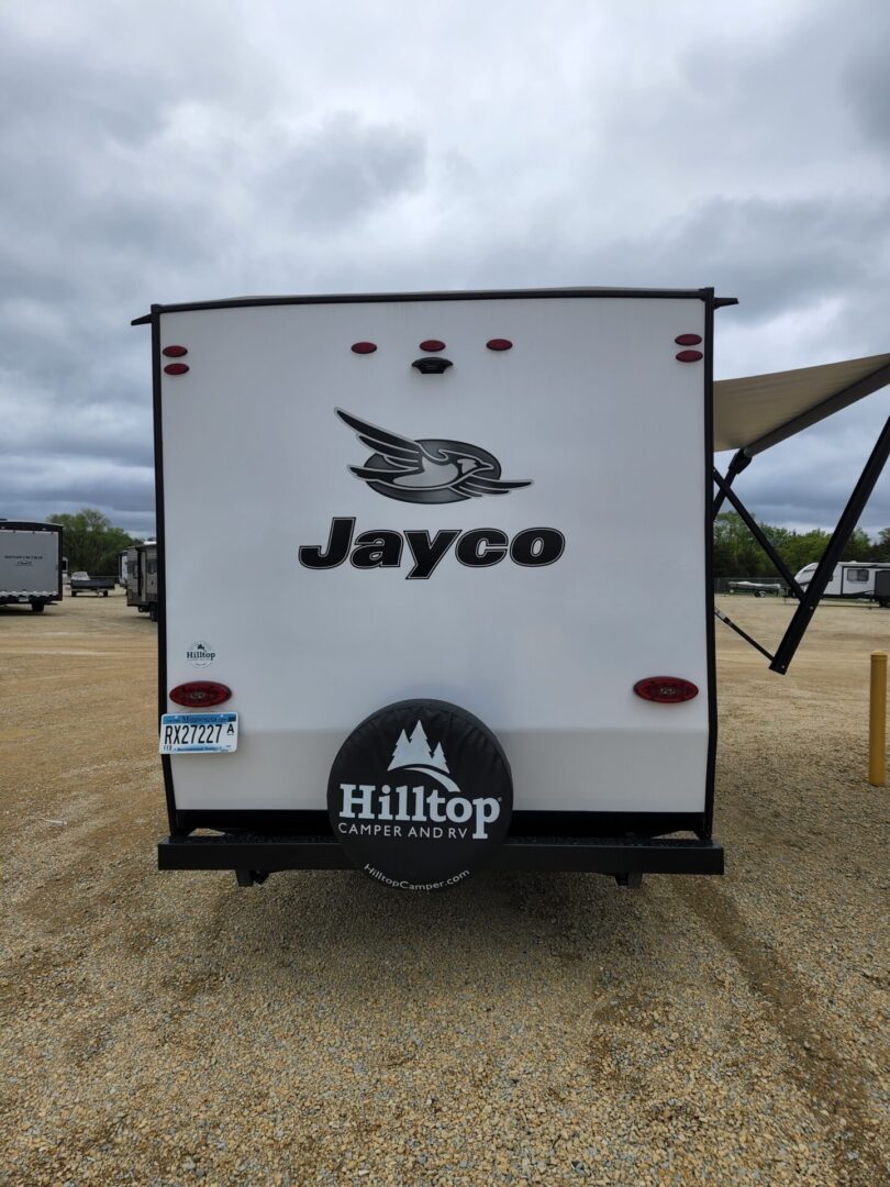 A white jayco trailer parked in the sand.